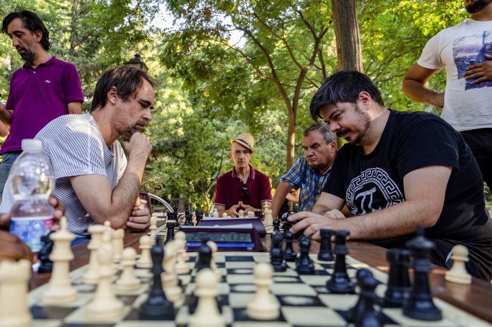 Dos personas jugando una partida de ajedrez, con varias personas observando